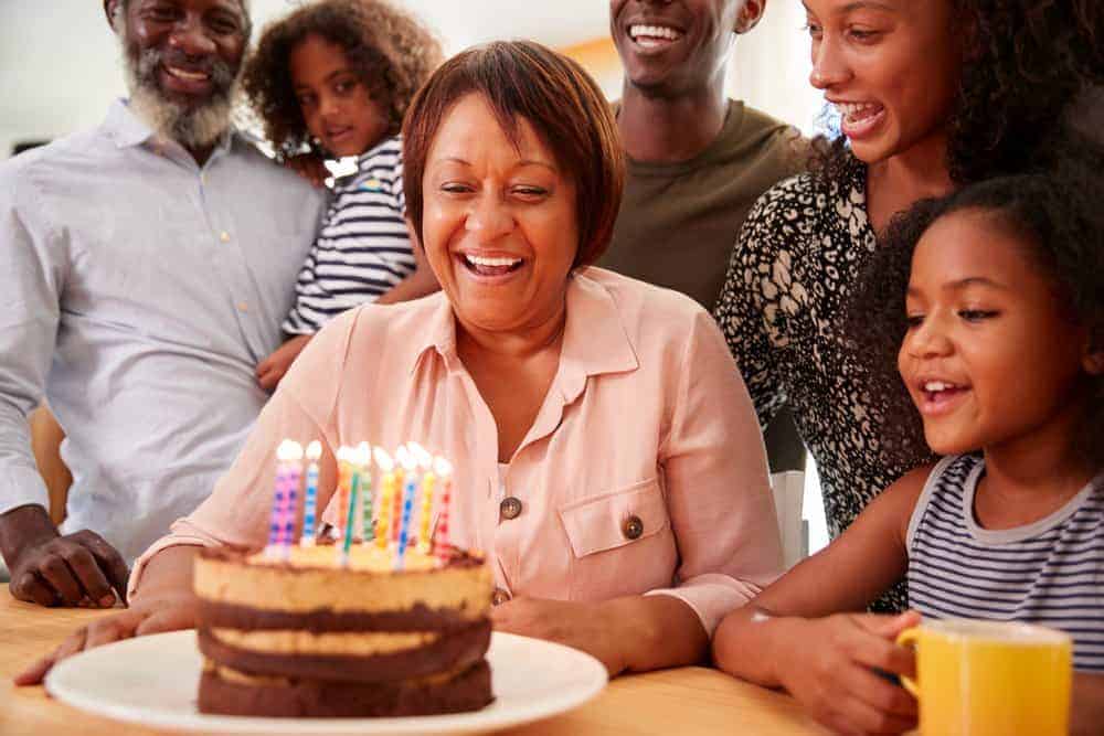 grandma smiling at birthday cake with family surrounding her