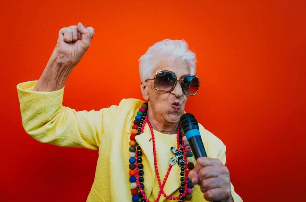 grandmother wearing colorful beaded jewelry rocking out in karaoke