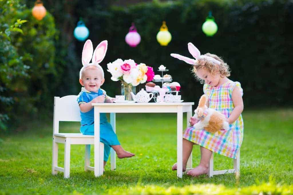 two children having an easter tea party at a table outside