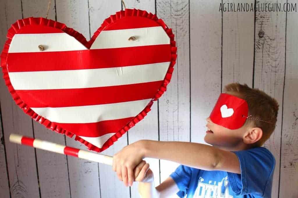 heart shaped pinata made by duct tape and boy wearing a blindfold hitting pinata