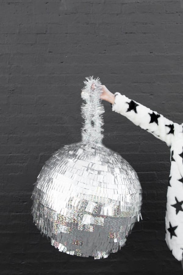 DIY disco ball pinata being held by an arm