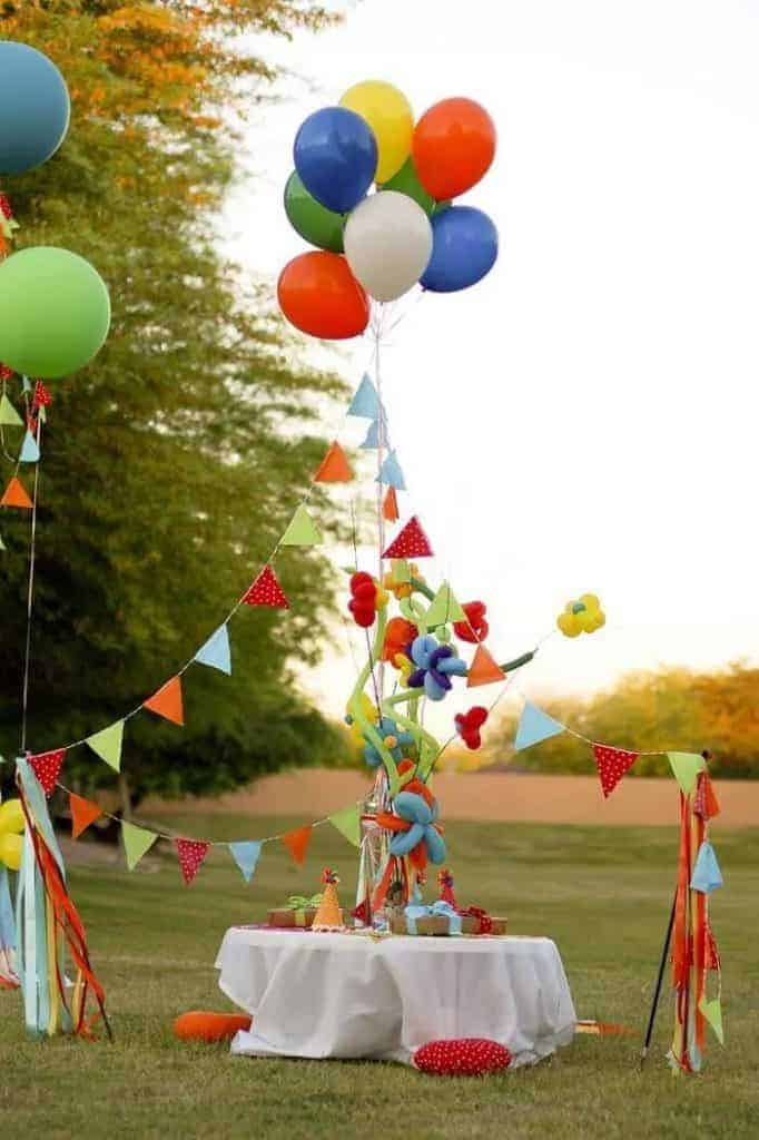 Elaborate party setup with balloons and pennant garland hung in the shape of a circus tents with fancy balloon twists on a pole