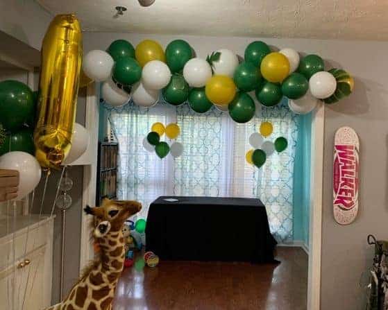 green, white and gold balloon garland hung over a doorway