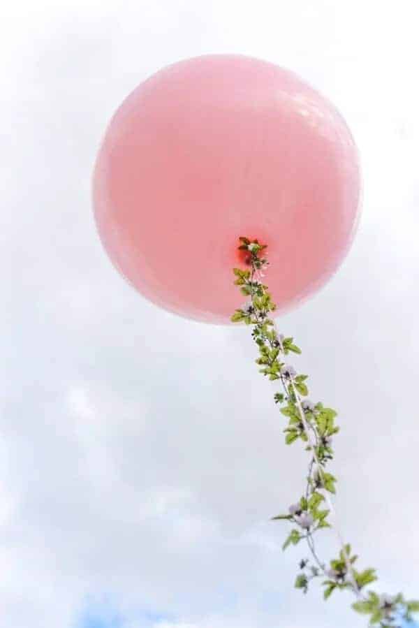 giant pink ballon with floral garland on the string shot from below