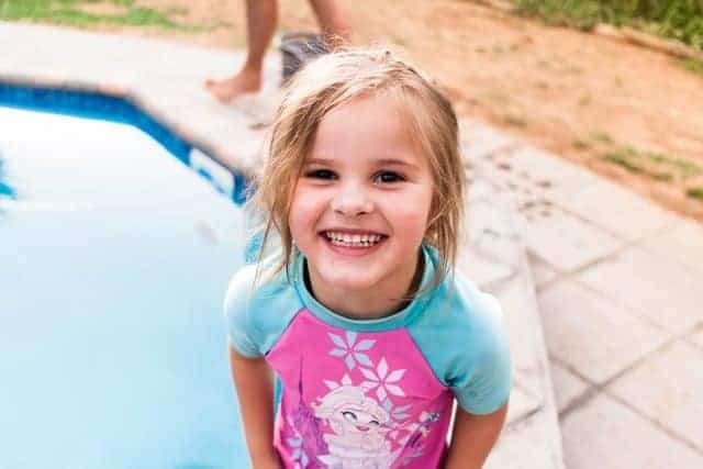 girl smiling standing at edge of swimming pool