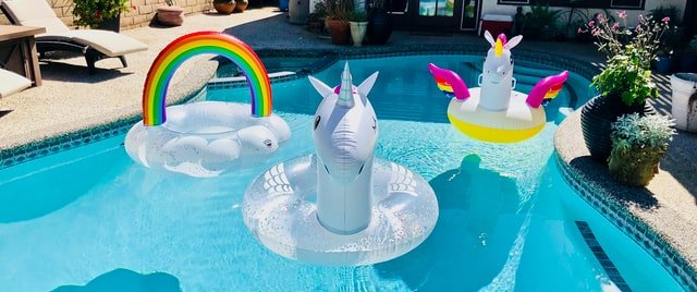 unicorn and rainbow pool floats in swimming pool