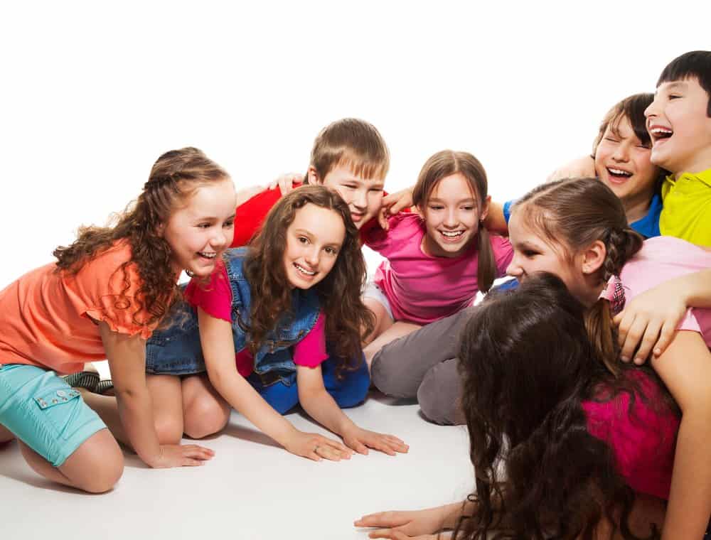 group of tweens crouched on the floor laughing and acting like they are playing a game