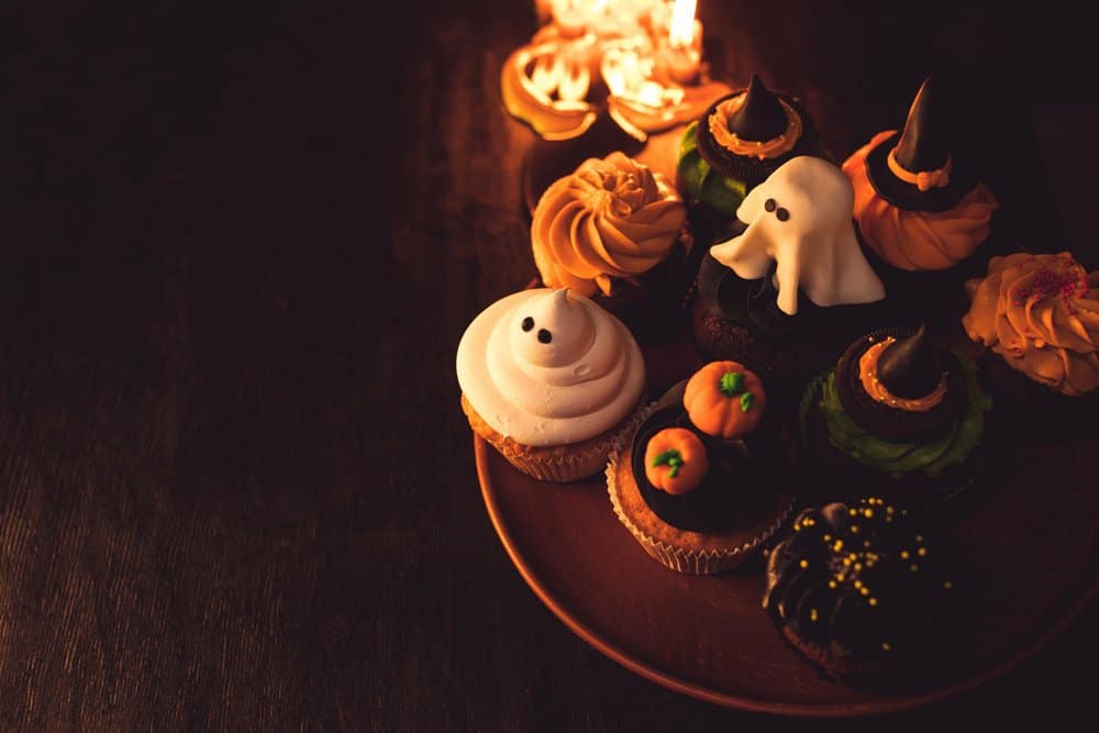 decorated halloween cupcakes with orange, black and white frosting and halloween themed candy