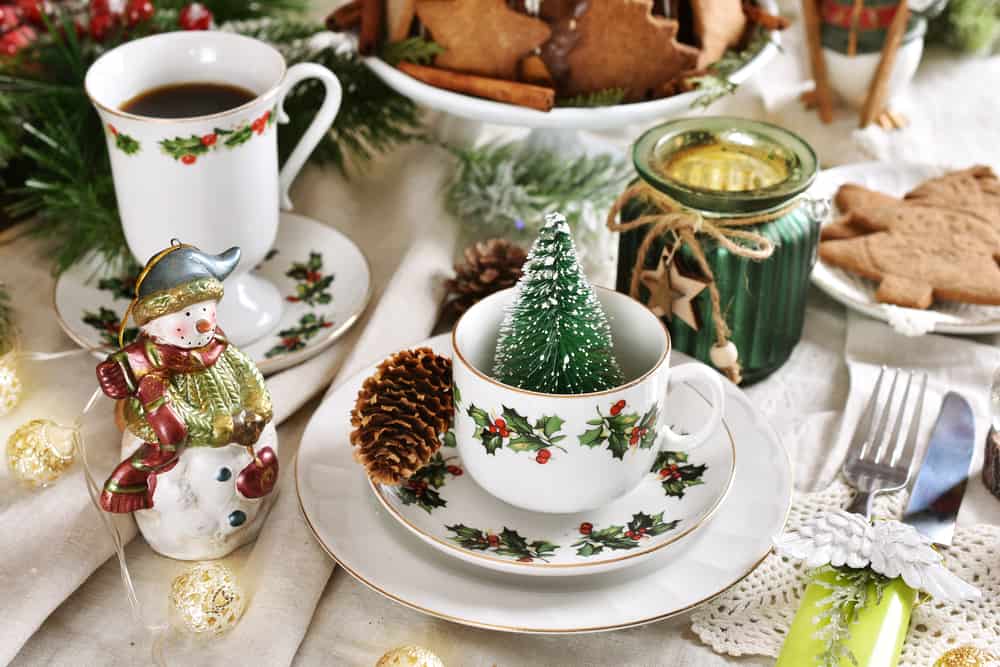 christmas tea set on a table with holiday tableware, gingerbread cookies and snowman decoration