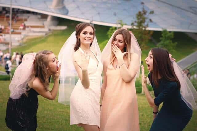 group of women making surprised faces as a bride to be holds up her engagement ring during a hen party