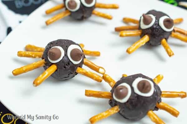 easy halloween donut spiders made out of donut holes, pretzels and chocolate chips on a plate