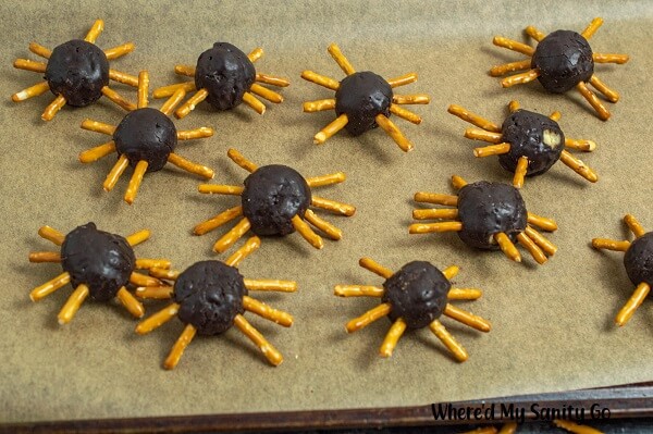 mini donut hole spiders with pretzels legs sitting on a tray