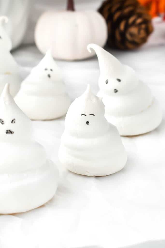 whippe meringue ghosts with black eyes sitting on a white counter