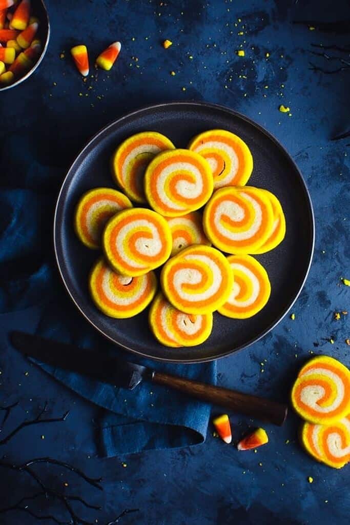 orange and yellow candy corn swirled cookies on a dark blue background