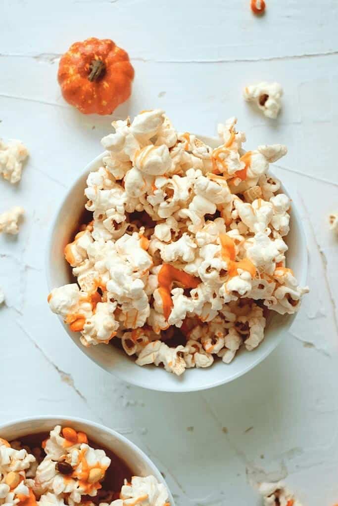 white and orange candied popcorn in a white bowl