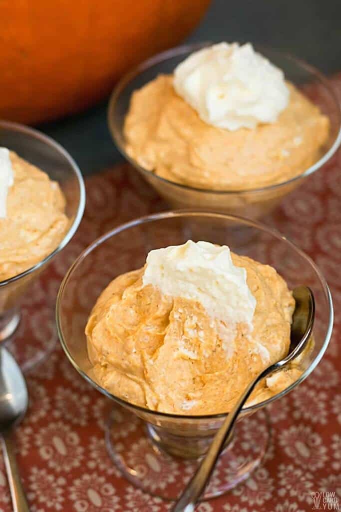 glass pudding cups with smooth pumpkin mousse and whipped cream with a spoon