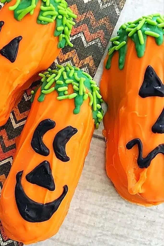 fun and easy halloween dessert consisting of a twinkie decorated like a jack-o-lantern with candy melts and sprinkles