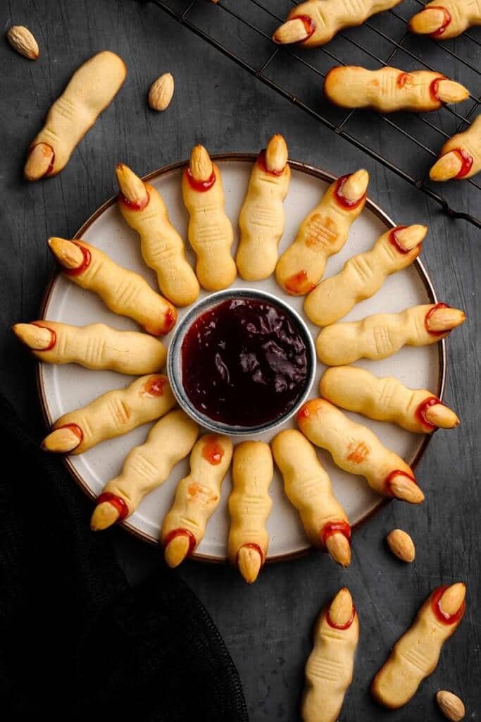 overhead view of realistic witch finger cookies with blood red dipping jam