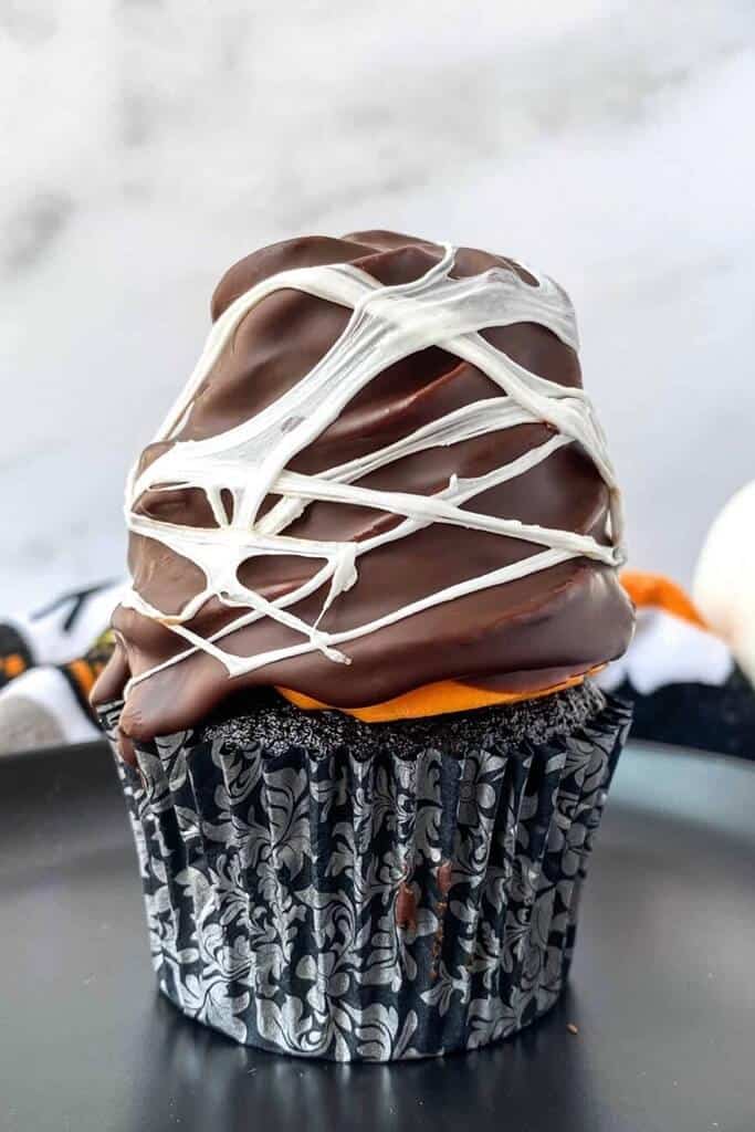 closeup of a witch hat cupcake with spiderweb drizzle