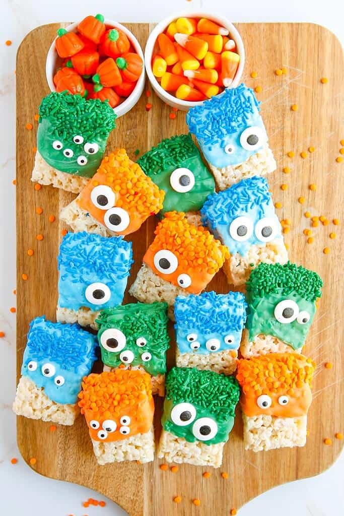 monster rice krispie treats on a wooden serving board with halloween candies