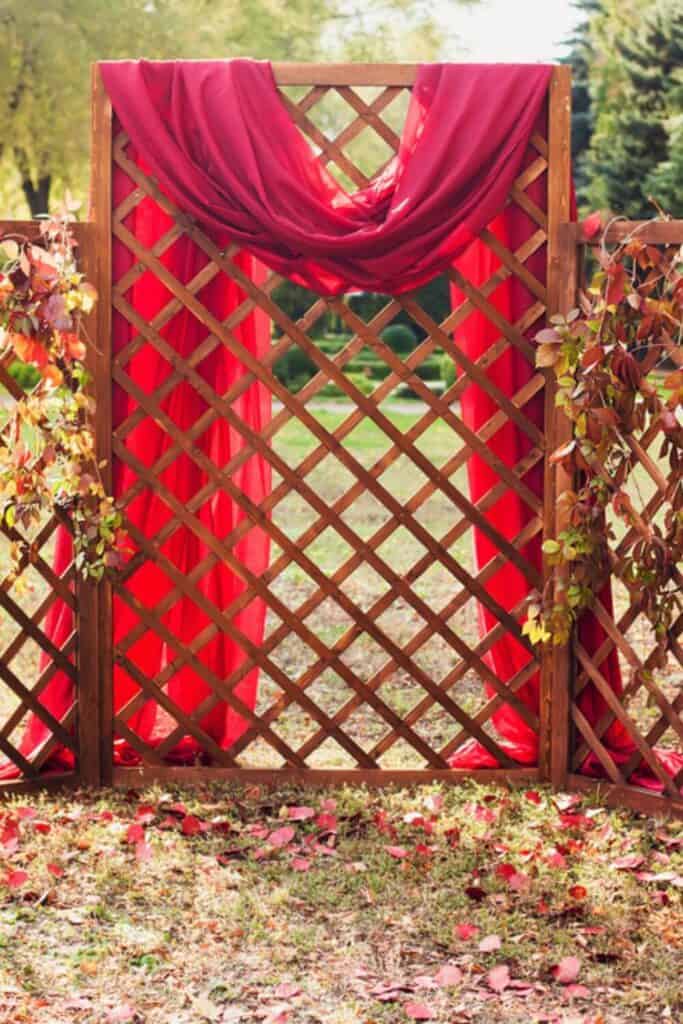 luxurious red draped fabric over a lattic boxed shaped wedding backdrop