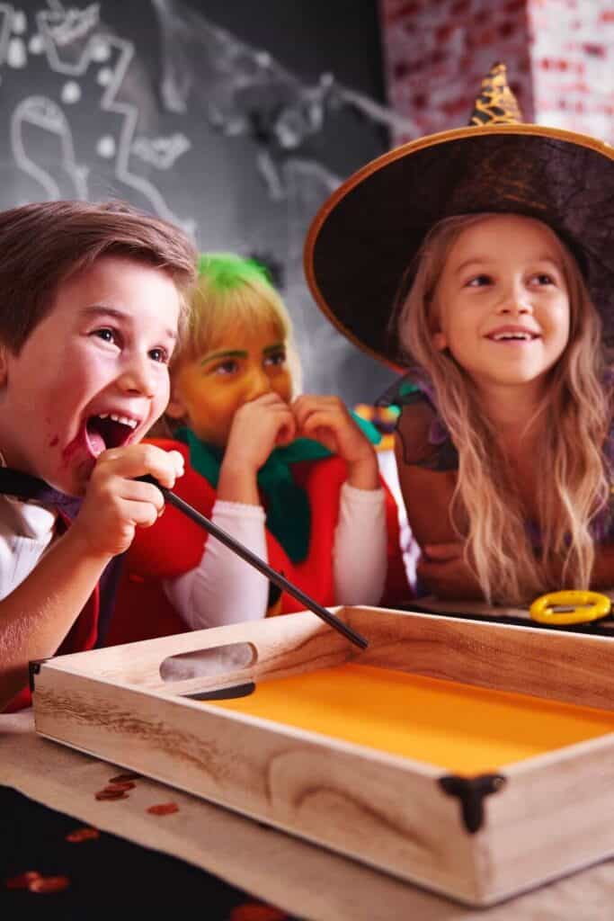 kids dressed up at halloween costume party laughing while playing a game with a straw
