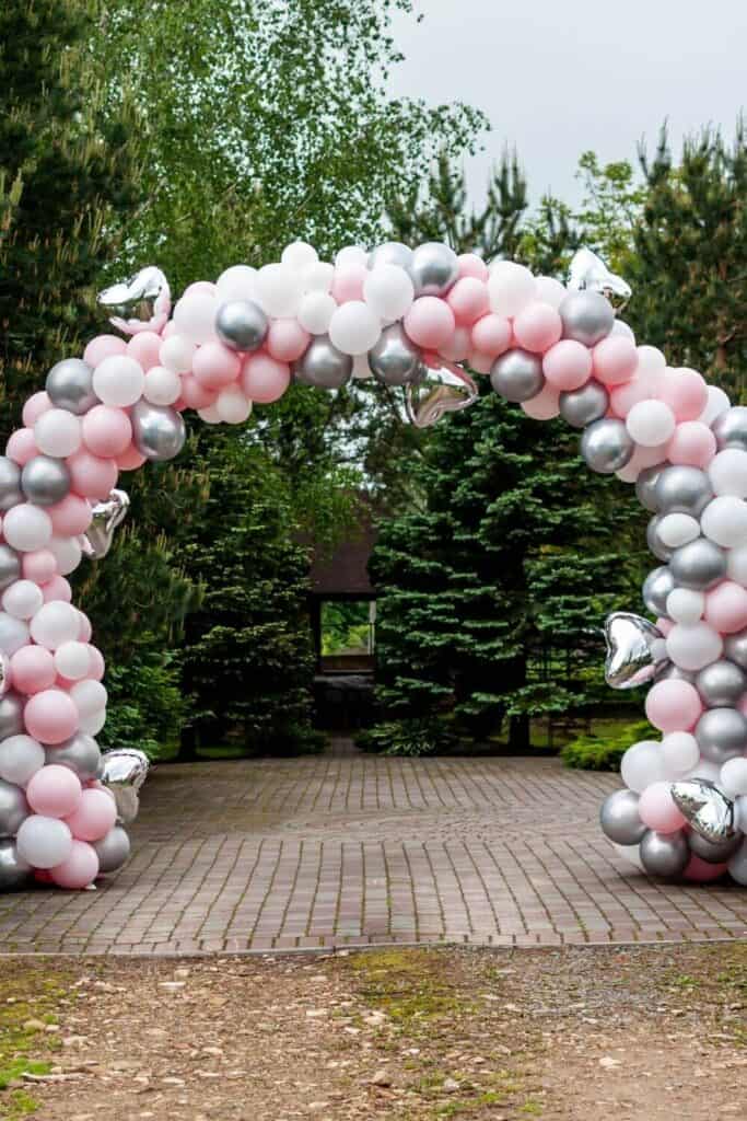 pink, white and silver balloon arch set up in an outdoors location